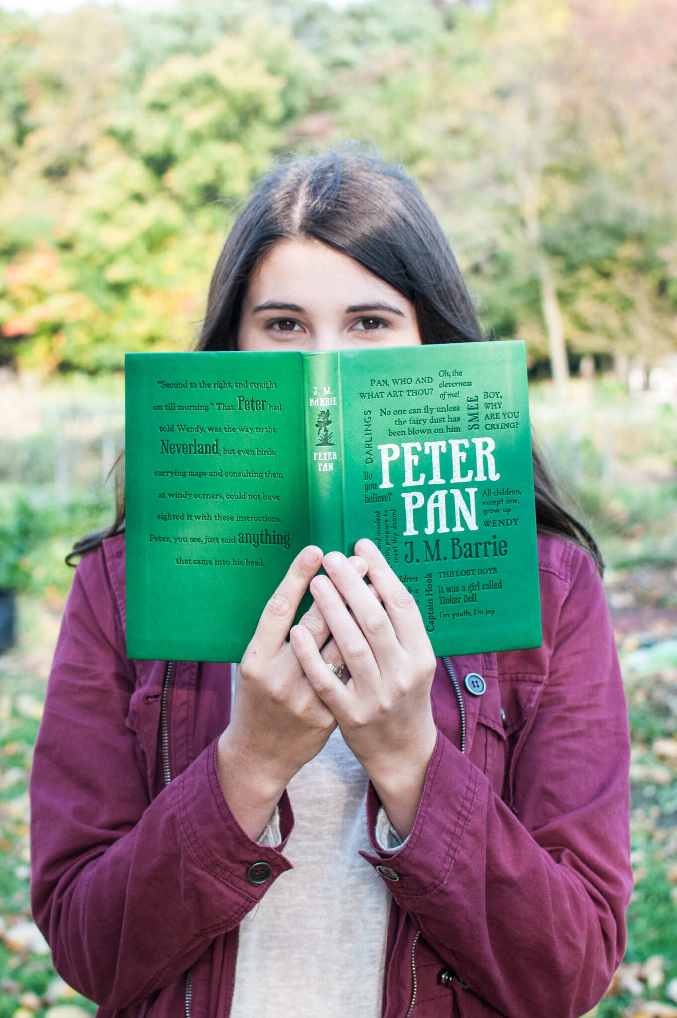 older girl peeking over Peter Pan book, Northville Senior Portrait Photographer