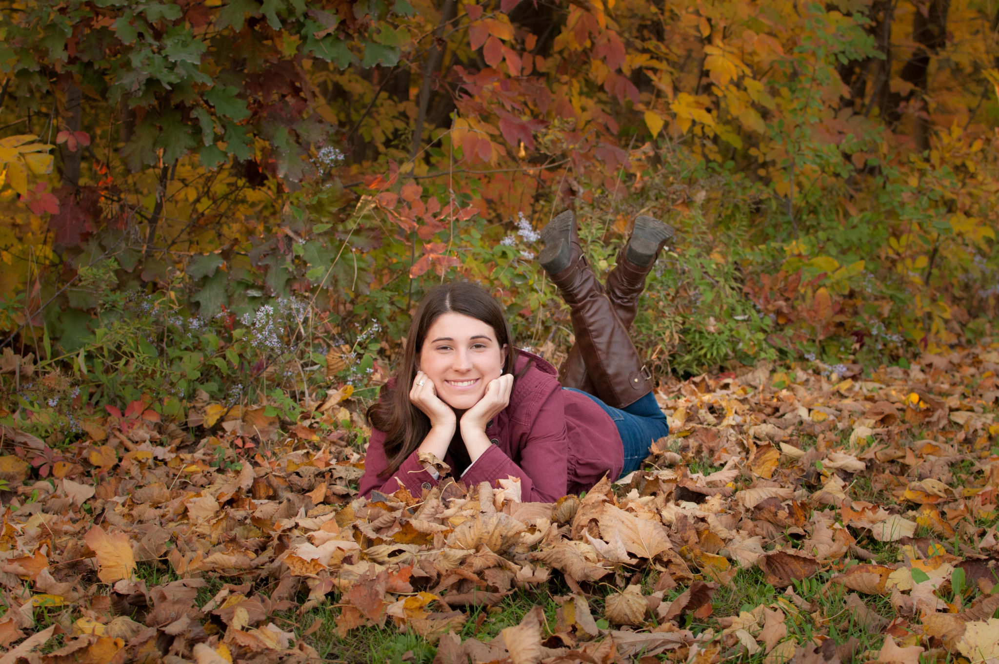 girl laying in leaves with feet kicked up, Metro Detroit Senior Photography