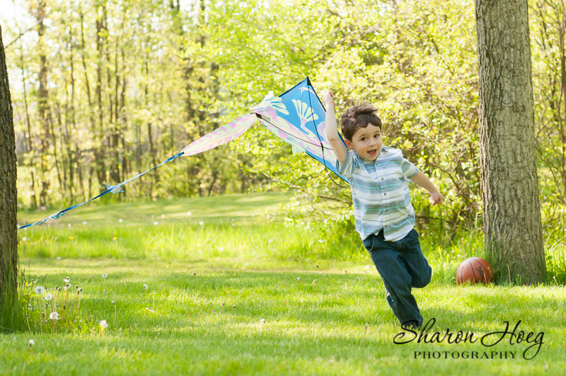 young boy in blue running with a long tail kite, Metro Detroit Child Portraits